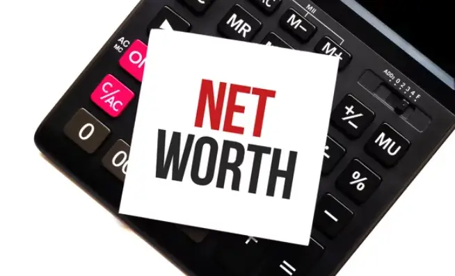 A black calculator with a post-it note that says Net Worth on it.