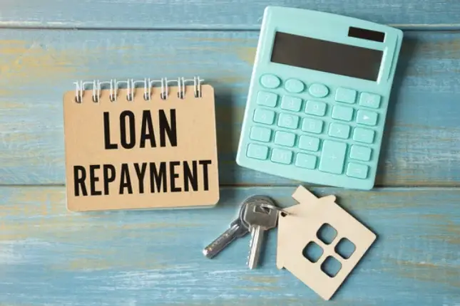An aqua-coloured calculator, a set of home keys, and a notepad with Loan Repayment written on it.